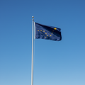 Alaska flag on flagpole with blue sky background